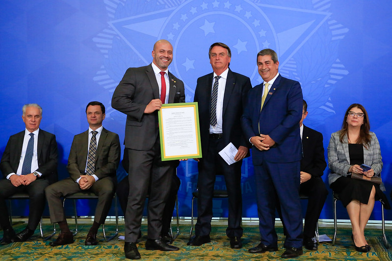 Deputado Daniel Silveira exibe quadro com graça presidencial ao lado de Bolsonaro durante encontro com parlamentares no Palácio do Planalto.
Foto: Anderson Riedel/PR