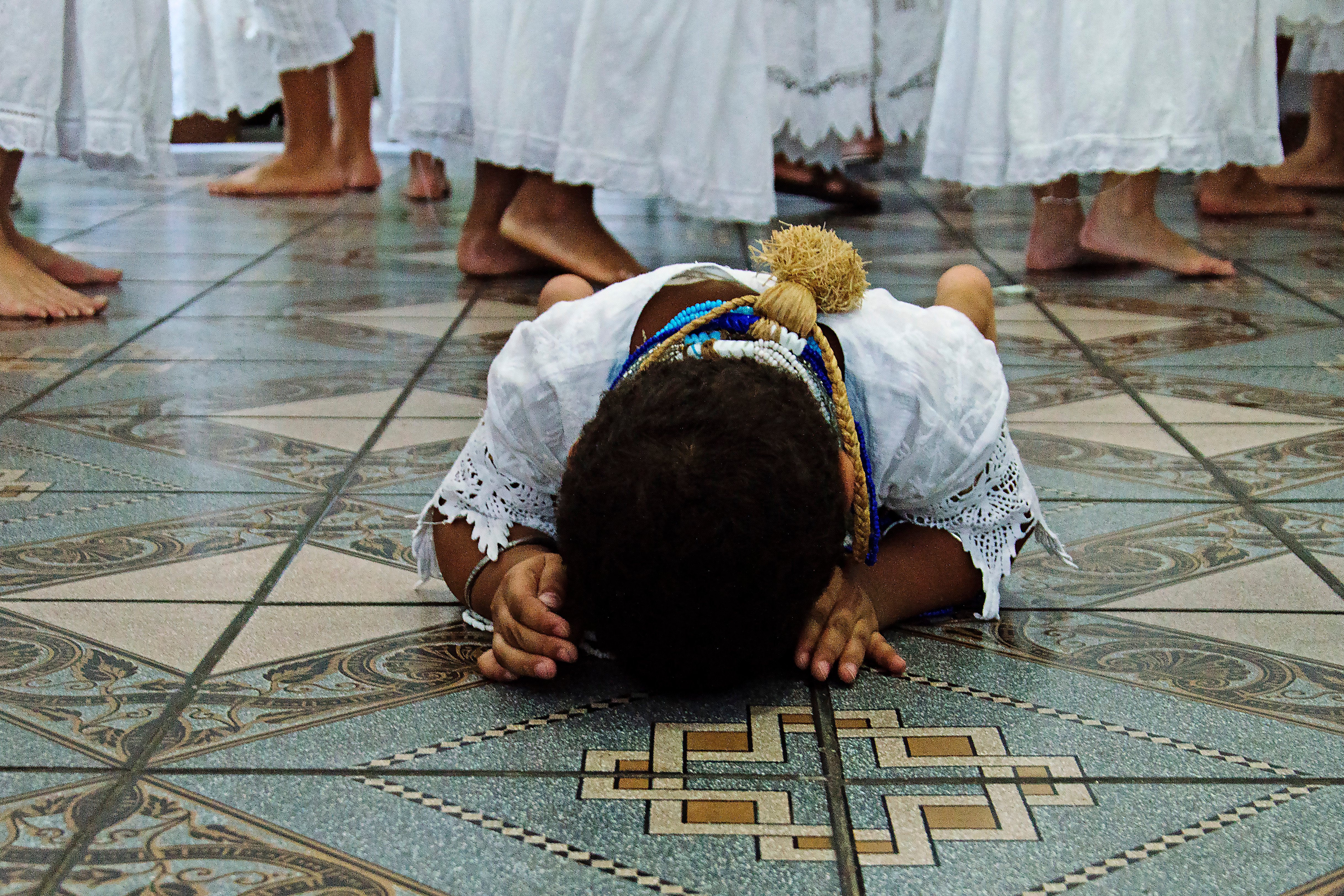 Iaô de Oxossi saúda o seu orixá ao levar sua cabeça ao chão no Ilê Axé D'Ogun-já. Foto: Mariana Maiara/Olhares Negros