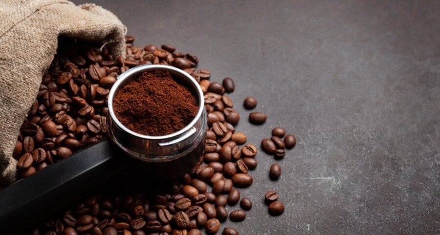 Roasted coffee beans and ground coffee in filter holder. With copy space