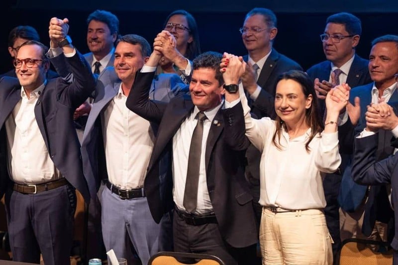 Sergio Moro segura a mão de Flávio Bolsonaro no ato de sua filiação ao PL nesta terça-feira em Brasília.