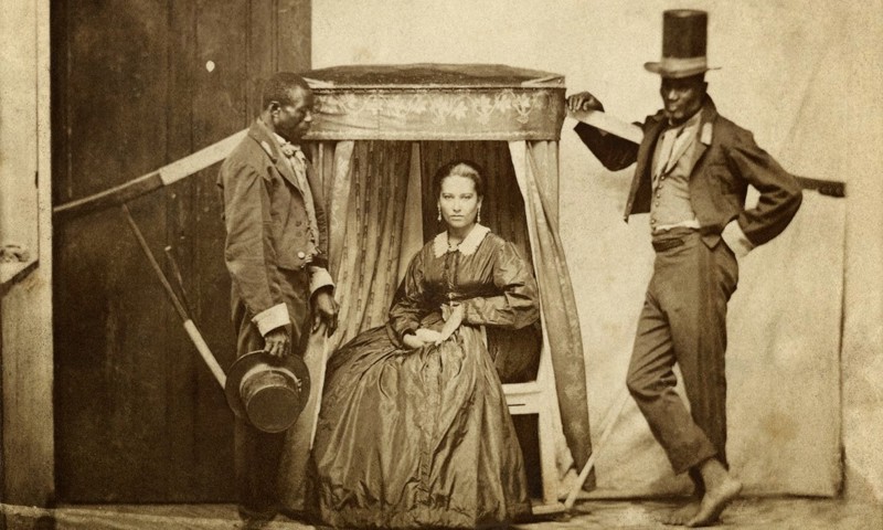Senhora em uma liteira e dois homens escravizados na Bahia em 1880.