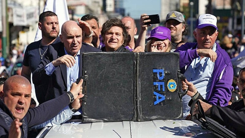 Seguranças protegem Javier Milei durante evento político marcado por tensão e confrontos com manifestantes.