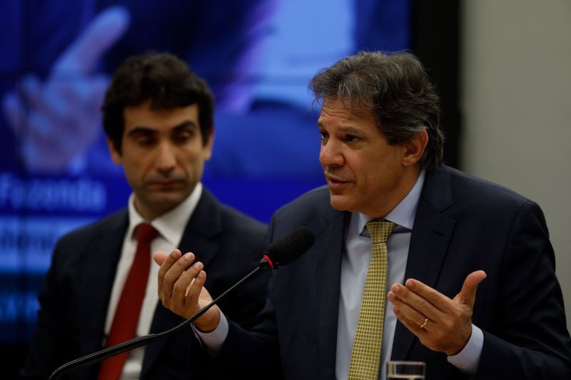 Fernando Haddad, falando, ao lado de Gabriel Galípolo. Ministro da Fazenda defendeu o presidente do BC após alta nos juros