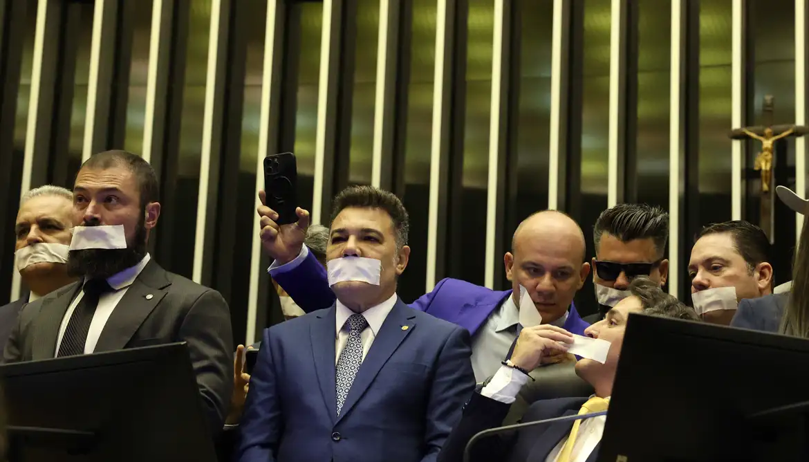 Com adesivo na boca, deputados bolsonaristas ocuparam a mesa da Câmara e por lá passaram toda a noite em protesto contra a prisão domiciliar do ex-presidente.
