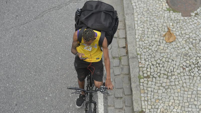 Trabalhador de entrega por aplicativo percorre ruas no centro do Rio de Janeiro.